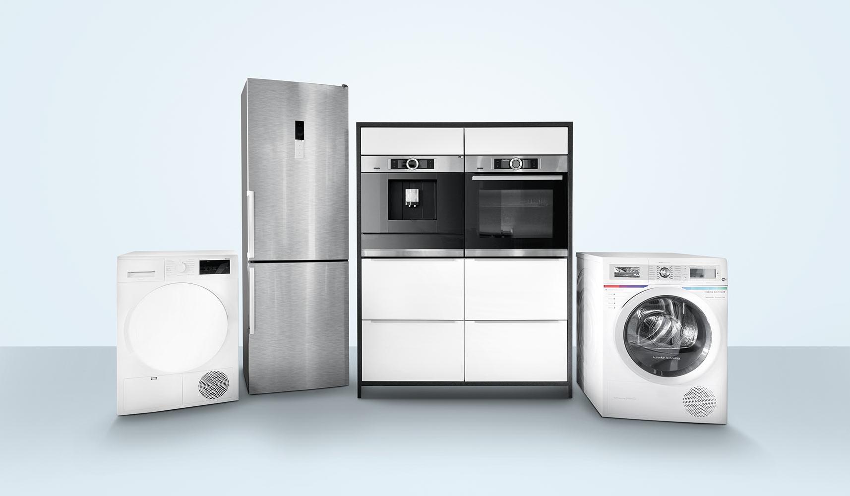 Wäschetrockner, Kühl-Gefrier-Kombigerät, Ausstellungsküchenblock mit Kaffeevollautomat und Backofen und Waschmaschine in leerem, neutralem Raum